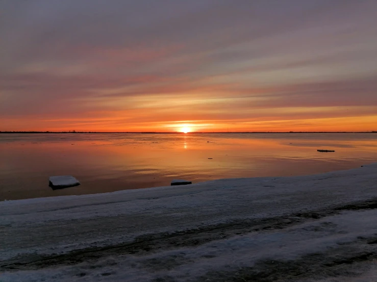 the sun is setting over a body of water, by Jan Tengnagel, pexels contest winner, winter setting, shoreline, wide horizon, inlets