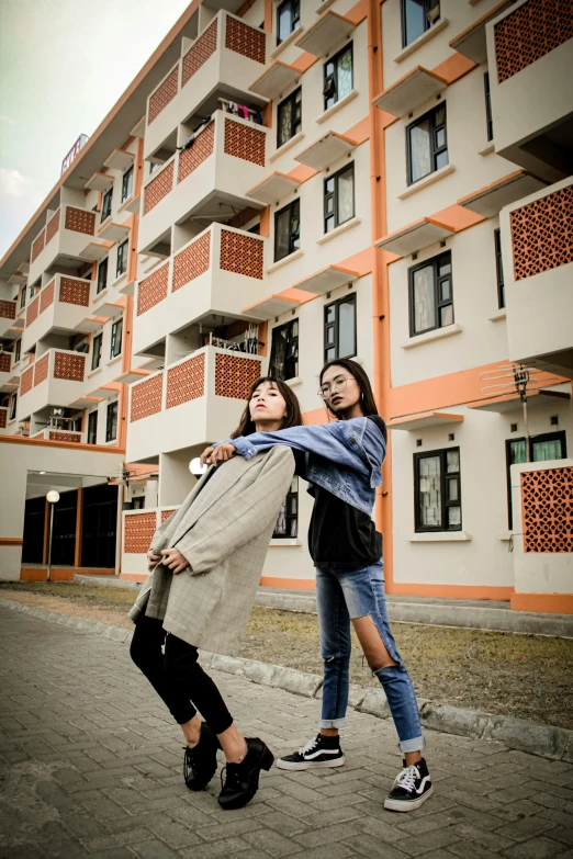 a couple of women standing next to each other in front of a building, by Bernardino Mei, unsplash, realism, apartments, nepali architecture buildings, 15081959 21121991 01012000 4k, model pose