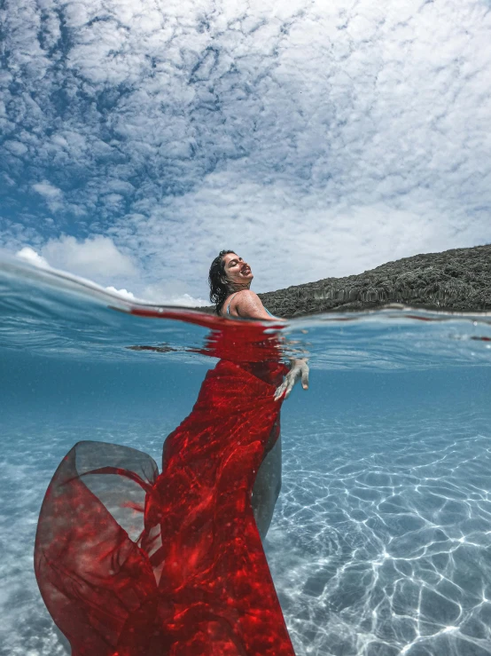 a woman in a red dress is in the water, an album cover, inspired by Scarlett Hooft Graafland, unsplash contest winner, samoan features, crystal clear blue water, taken in 2022, elegant pose