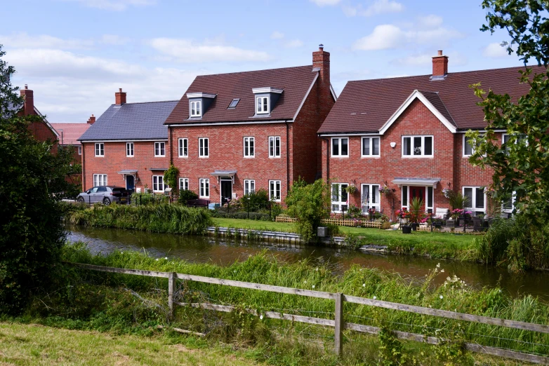 a row of houses next to a body of water, a photo, by Bertram Brooker, shutterstock, arts and crafts movement, blocked drains, countryside, mixed development, slide show