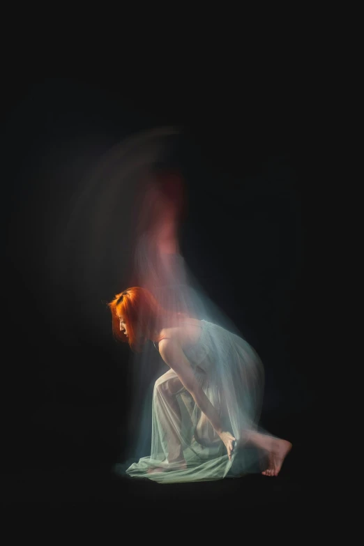 a woman in a white dress sitting on the ground, by Elizabeth Polunin, light and space, long orange hair floating on air, on black background, studio medium format photograph, iridescent ethereal veils