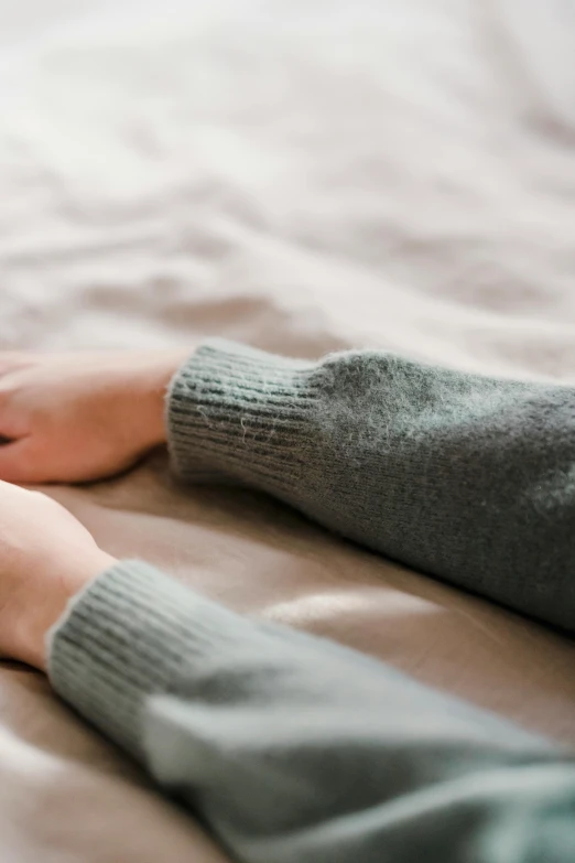 a close up of two people holding hands on a bed, by Ruth Simpson, grey sweater, worn pants, soft volume absorbation, in a chill position