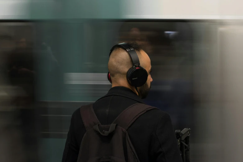 a man with headphones standing in front of a train, pexels contest winner, hyperrealism, back of head, central station in sydney, panning shot, no - text no - logo