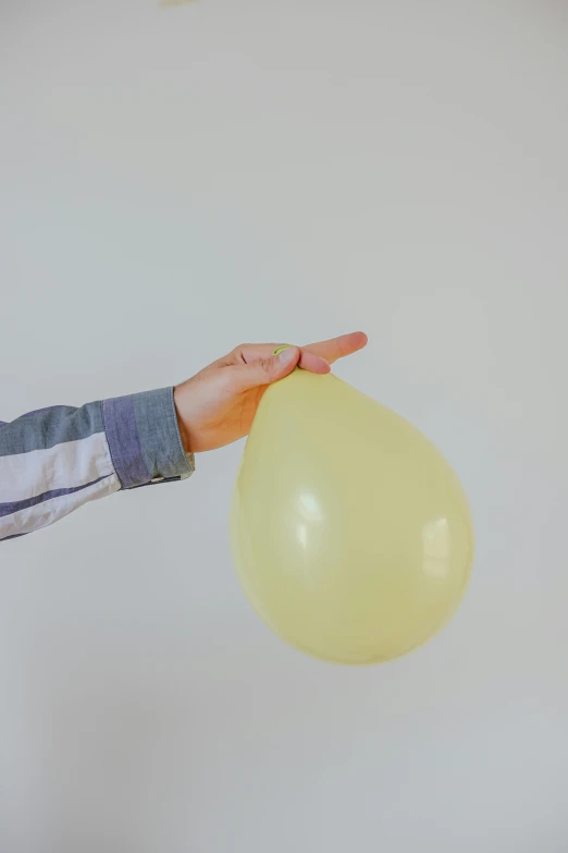 a person holding a yellow balloon in their hand, when it's over, inflateble shapes, very pale, press shot