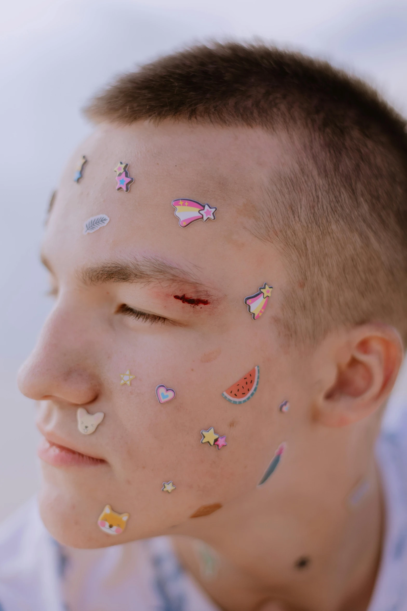 a man with lots of stickers on his face, by Julia Pishtar, trending on pexels, renaissance, holo sticker, smooth pale skin, teen boy, dim stars as eyes