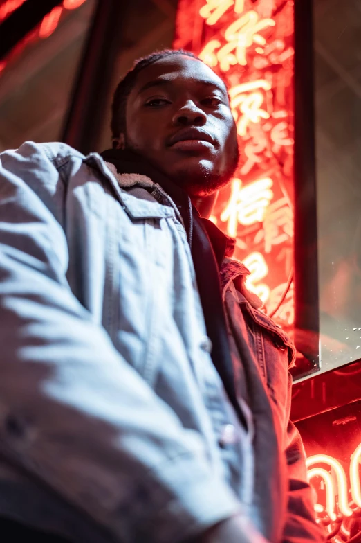 a man standing in front of a neon sign, trending on pexels, dark skinned, red and cinematic lighting, model posing, reflective lighting