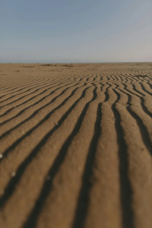 a person riding a surfboard on top of a sandy beach, unsplash, land art, subtle pattern, highly detailed in 4k, erosion, striped