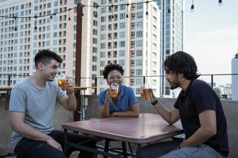 three people sitting at a table drinking beer, city rooftop, avatar image, ignant, diverse