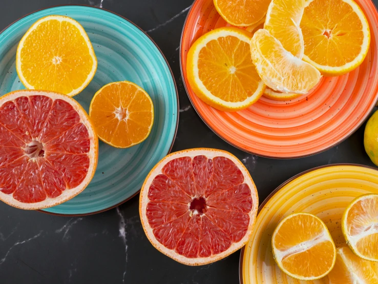 a table topped with plates filled with oranges and lemons, trending on pexels, striped orange and teal, bowl of fruit, sliced grapefruit, dark orange