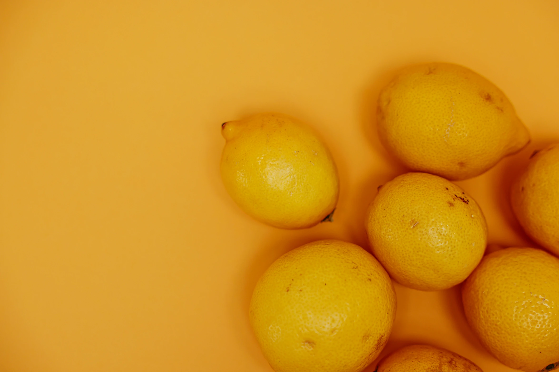 a bunch of lemons sitting on top of a table, detailed product image, in front of an orange background, low quality photo, high quality product image”