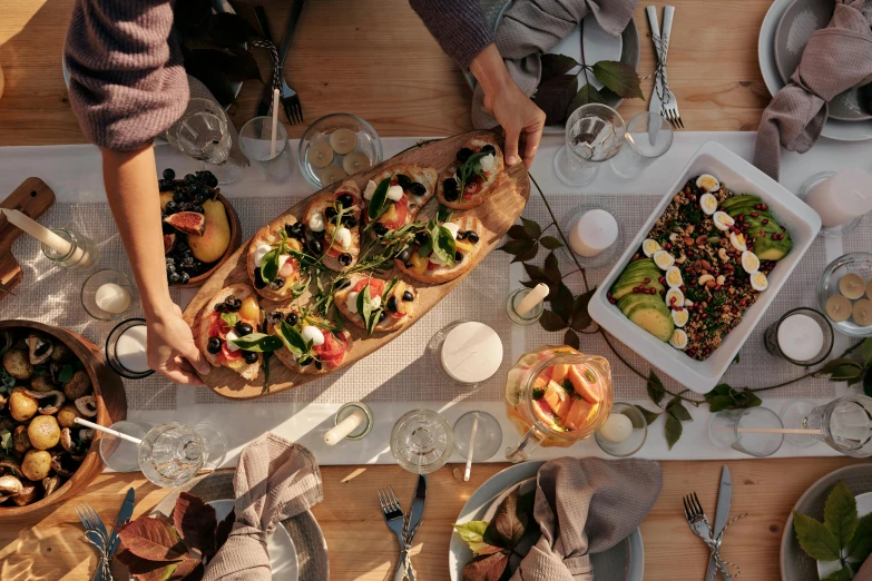 a group of people sitting at a table with plates of food, a still life, by Carey Morris, pexels contest winner, winter sun, long table, on a wooden tray, recipe