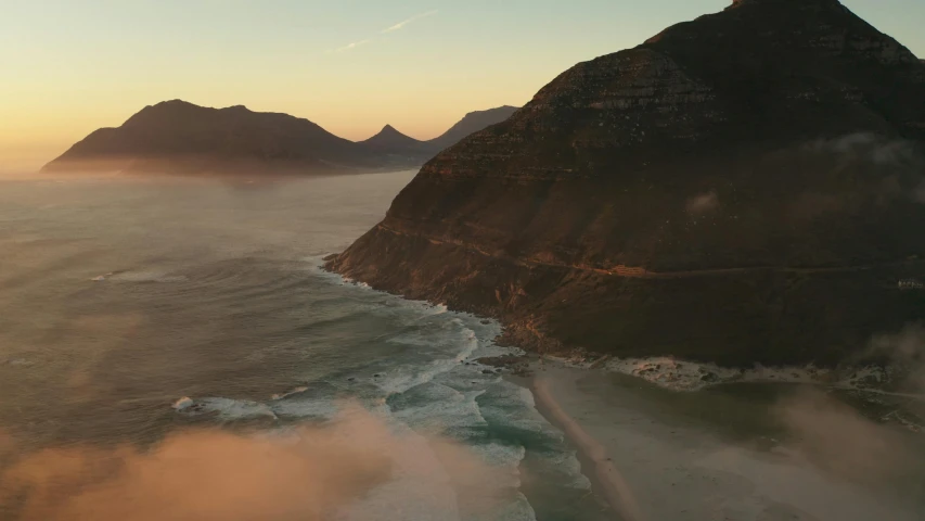 a view of the ocean with mountains in the background, by Daniel Lieske, pexels contest winner, cape, aerial footage, in a sunset haze, cinematic establishing shot