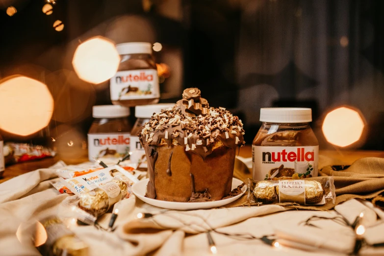a cake sitting on top of a table next to a jar of nutella, by Julia Pishtar, festive, various posed, 6 pack, lit from behind