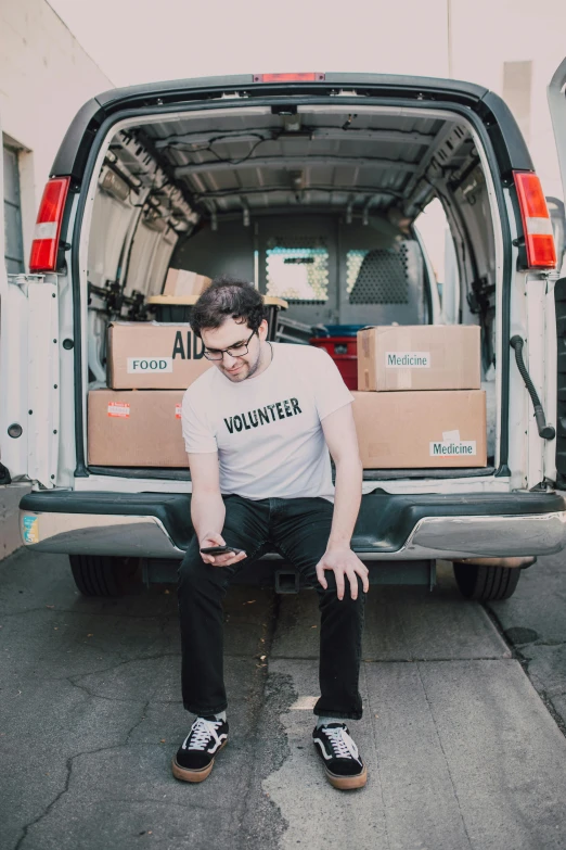 a man sitting in the back of a van, adafruit, curated collections, portrait image