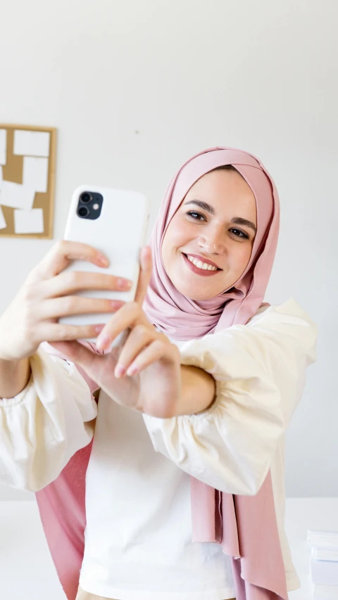 a woman taking a selfie with her cell phone, inspired by Charly Amani, white hijab, tiktok, half onesided smile, profile picture 1024px