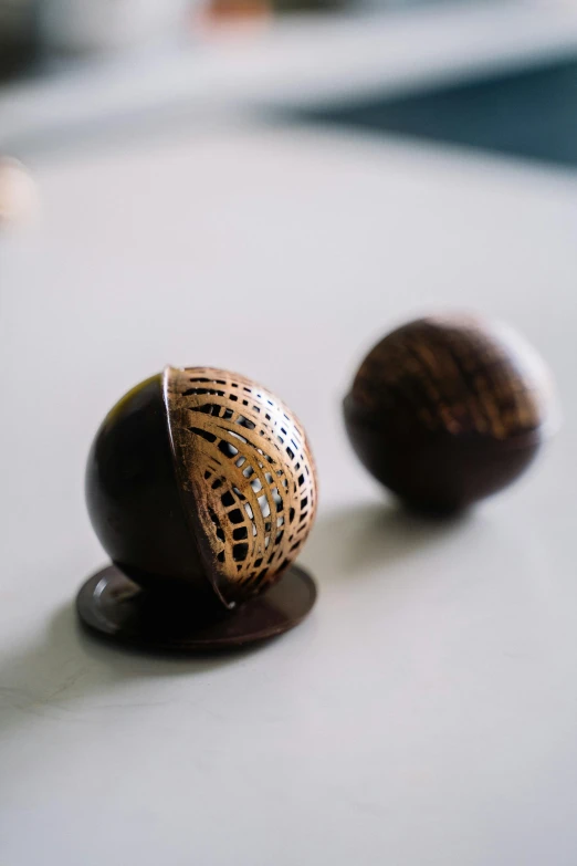 a couple of chocolate balls sitting on top of a table, renaissance, intricate lining, smooth surface, 35mm, 3 / 4 shot