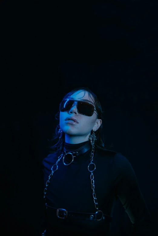 a woman in a black outfit and sunglasses, inspired by Elsa Bleda, unsplash, neck chains, dark. studio lighting, charli xcx, black and blue