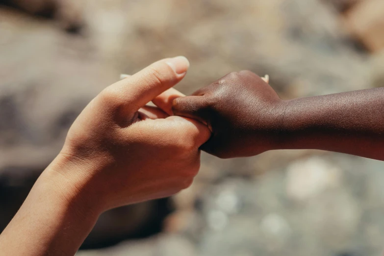 a close up of a person holding a child's hand, by Emma Andijewska, trending on unsplash, with brown skin, peace sign, calmly conversing 8k, panel of black