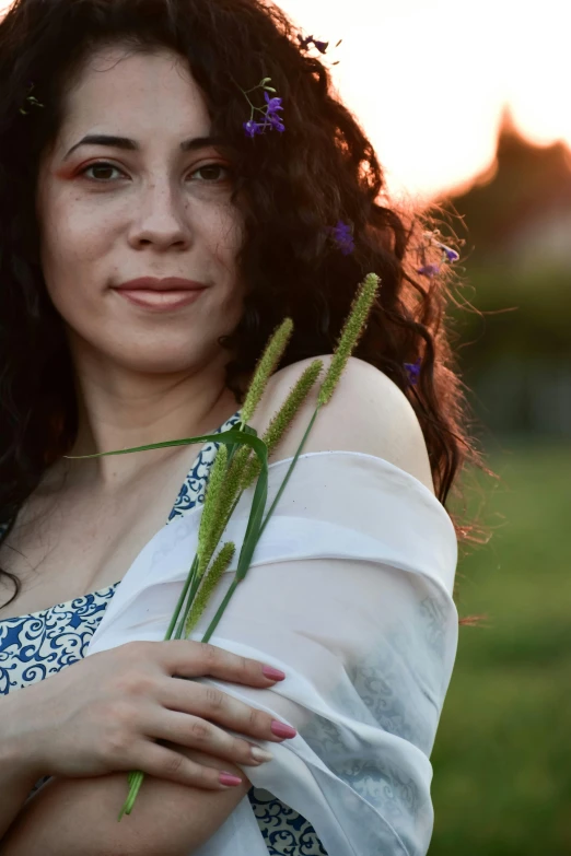 a woman standing in a field holding a flower, pexels contest winner, renaissance, young middle eastern woman, avatar image, curls, soft evening lighting