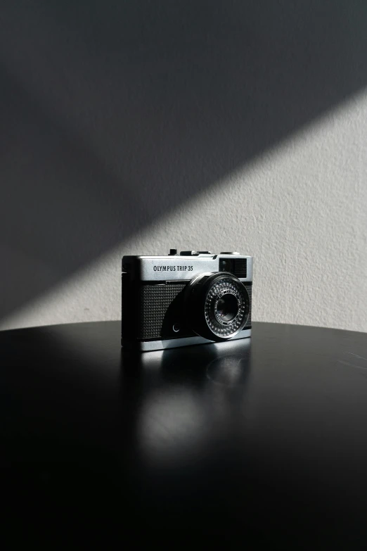 a camera sitting on top of a black table, a picture, by Sven Erixson, unsplash, photorealism, on a pale background, olympus, back - lit, front side