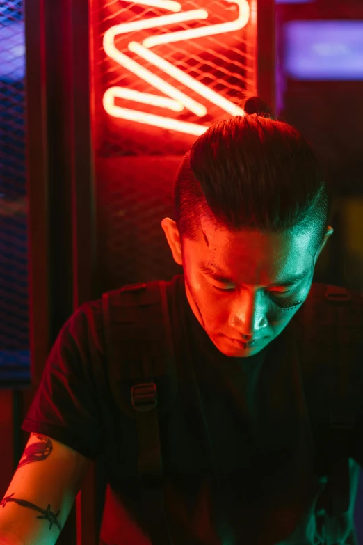 a man sitting at a table in front of a neon sign, an album cover, inspired by Jason Teraoka, pexels contest winner, looking serious, cinematic and dramatic red light, asian man, tattoo artist