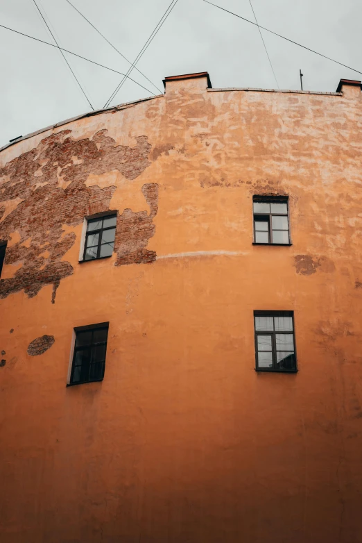 a tall orange building with lots of windows, inspired by Elsa Bleda, pexels contest winner, graffiti, capital of estonia, faded chipped paint, castle wall, rounded corners