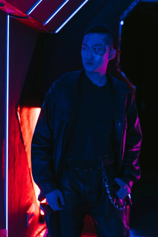 a man standing in front of a red light, inspired by Nan Goldin, unsplash, purple and blue leather, cai xukun, dark. studio lighting, photograph of a techwear woman