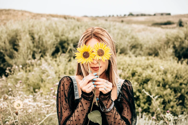 a woman holding a sunflower in front of her face, pexels contest winner, young beautiful hippie girl, holding a 🛡 and an 🪓, avatar image, having a good time