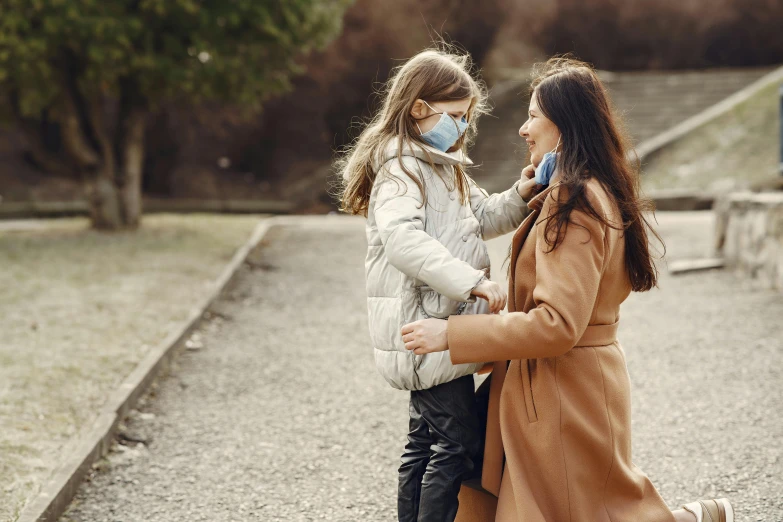 a woman standing next to a little girl wearing a face mask, by Emma Andijewska, pexels, walking at the park, coat, flirting, avatar image