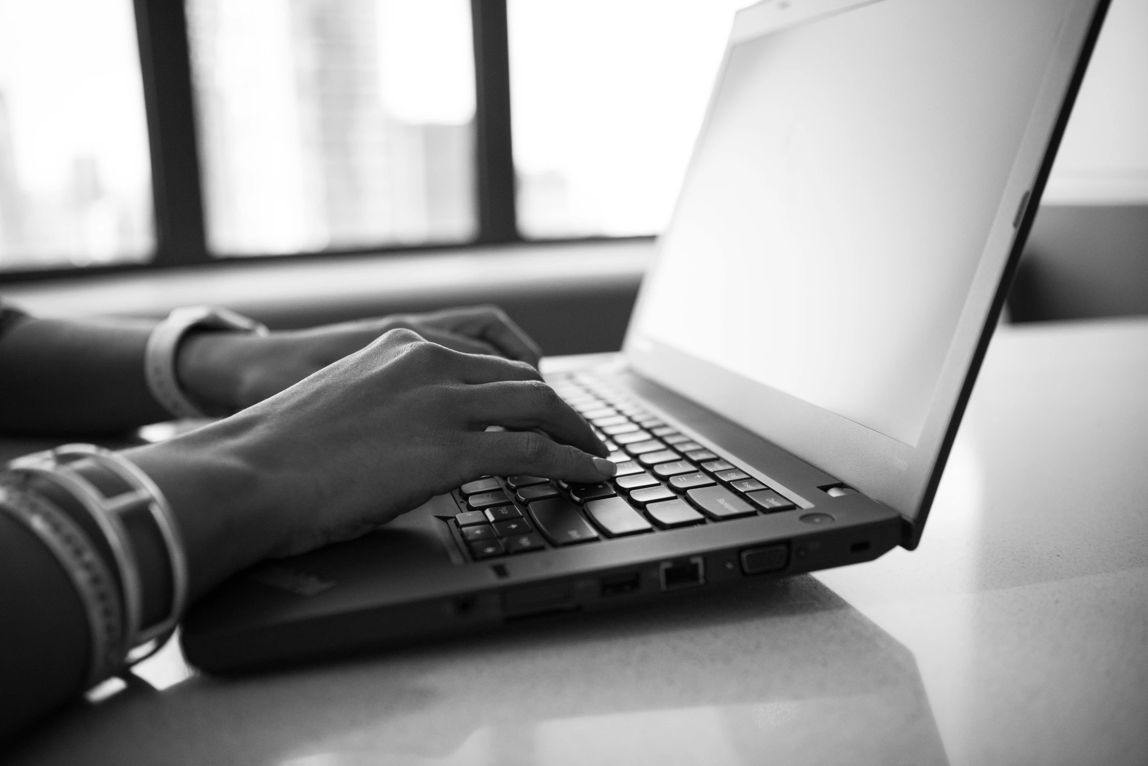 a black and white photo of a person typing on a laptop, by Emma Andijewska, photostock, uploaded, realistic »