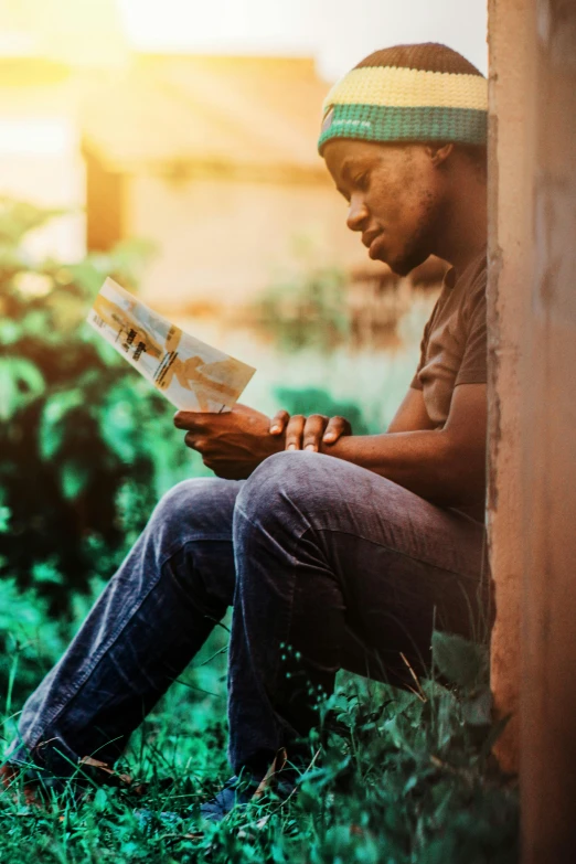 a man sitting in the grass reading a book, a picture, pexels contest winner, black teenage boy, village girl reading a book, distressed, profile pic