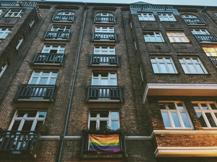 a tall brick building with a rainbow flag on it, by Emma Andijewska, unsplash, 1940s photo, fancy apartment, 🚿🗝📝