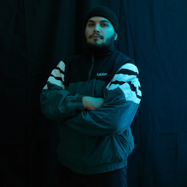 a man standing in front of a black backdrop, an album cover, unsplash, realism, wearing a track suit, twitch streamer / gamer ludwig, confident pose, indoor picture