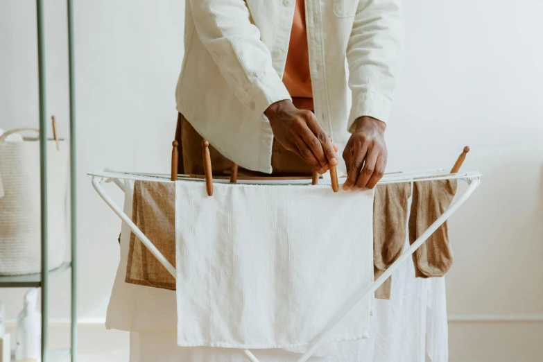 a man ironing clothes on a clothes line, trending on unsplash, brown and white color scheme, plain background, hands pressed together in bow, sustainable materials