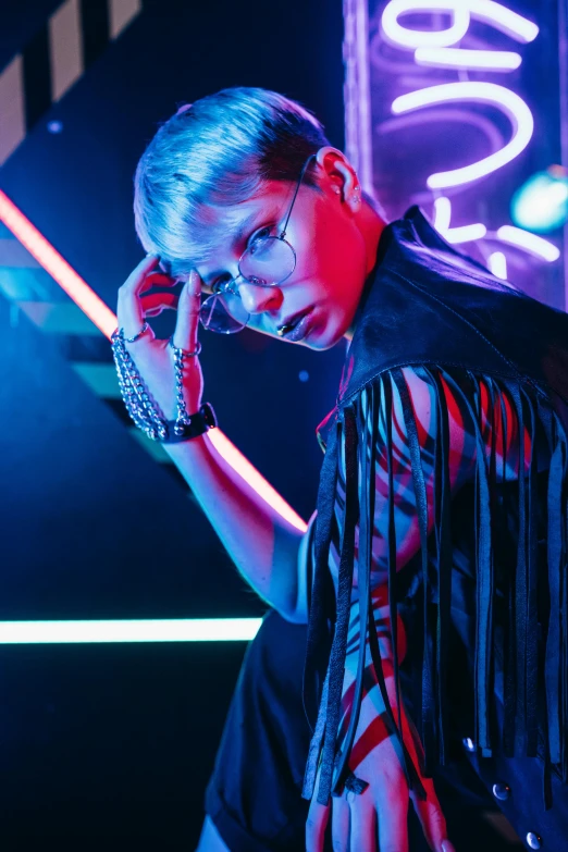 a woman standing in front of a neon sign, an album cover, trending on pexels, holography, androgynous vampire, reflecting light in a nightclub, with glasses, androgynous male