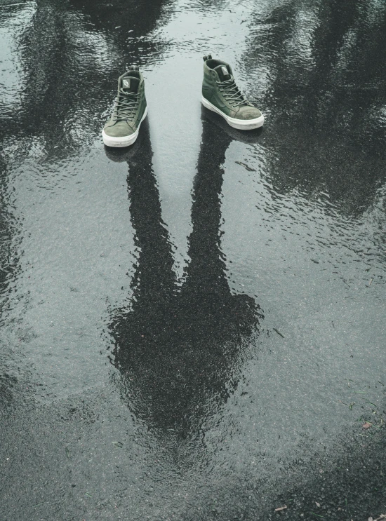 a pair of shoes sitting on top of a puddle of water, eerie person silhouette, green rain, unsplash photography, multiple stories