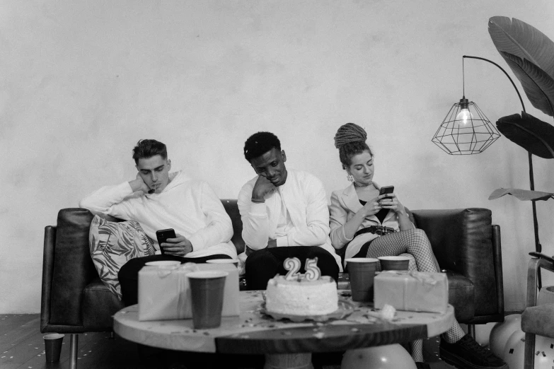 a black and white photo of three people sitting on a couch, by Maurycy Gottlieb, pexels, renaissance, reading for a party, looking at his phone, 1 9 5 0 s style, eating cakes