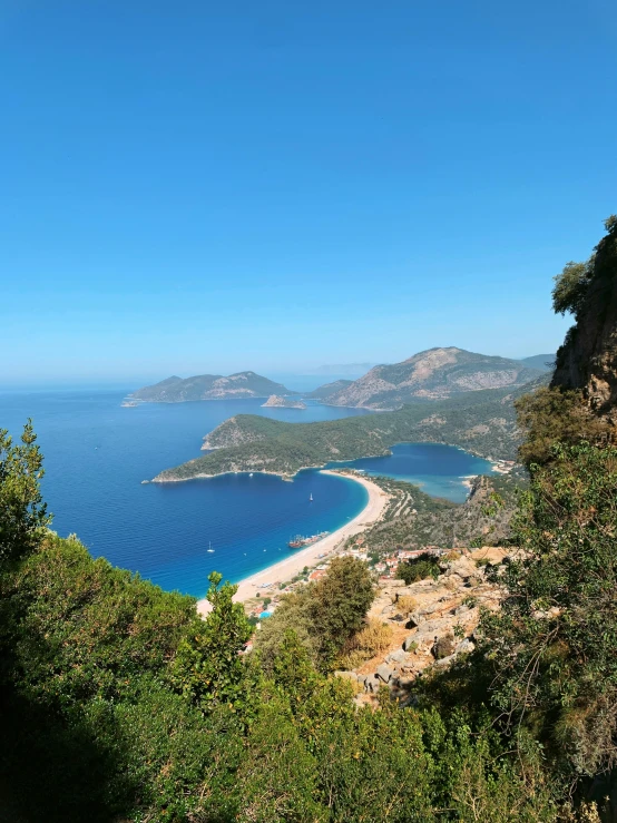 a large body of water sitting on top of a lush green hillside, by Cafer Bater, hurufiyya, overlooking the beach, behind that turquoise mountains, stunning 8 k, slide show