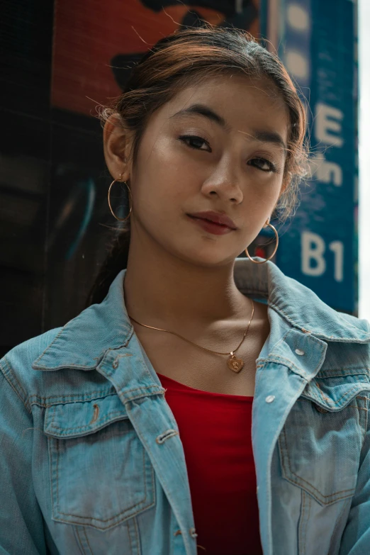 a woman holding a cell phone to her ear, an album cover, inspired by Feng Zhu, trending on pexels, hyperrealism, jean jacket, young asian girl, small necklace, street pic