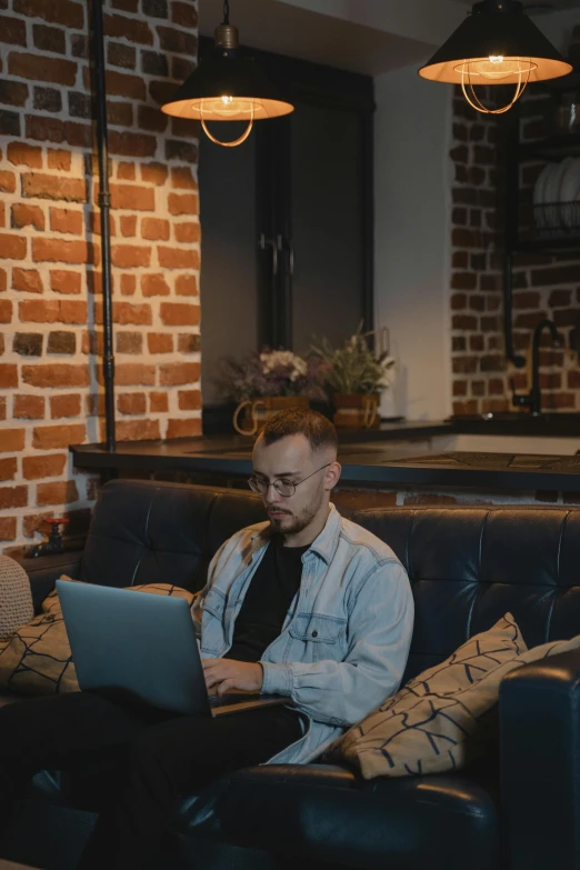 a man sitting on a couch using a laptop, by Adam Marczyński, trending on pexels, renaissance, non-binary, low - lighting, headshot, official screenshot