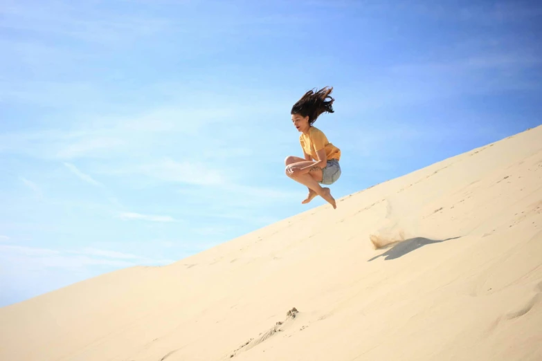a woman jumping in the air on top of a sand dune, by Liza Donnelly, pexels contest winner, arabesque, hair blowing, australian, slide show, profile image