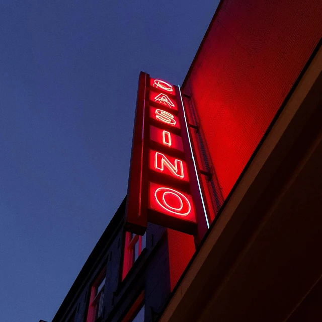 a neon sign on the side of a building, a photo, unsplash, casino, red and obsidian neon, clemens ascher, multiple stories