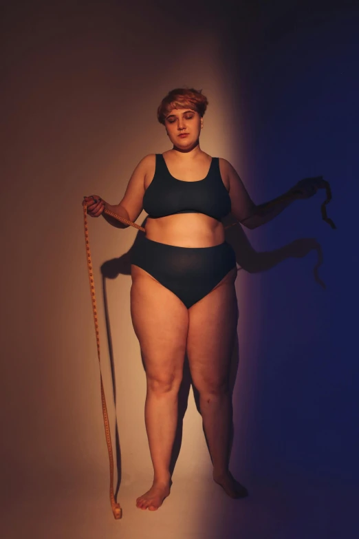 a woman with a tape around her waist, trending on pexels, a portrait of a plump woman, nonbinary model, cane, blue undergarments