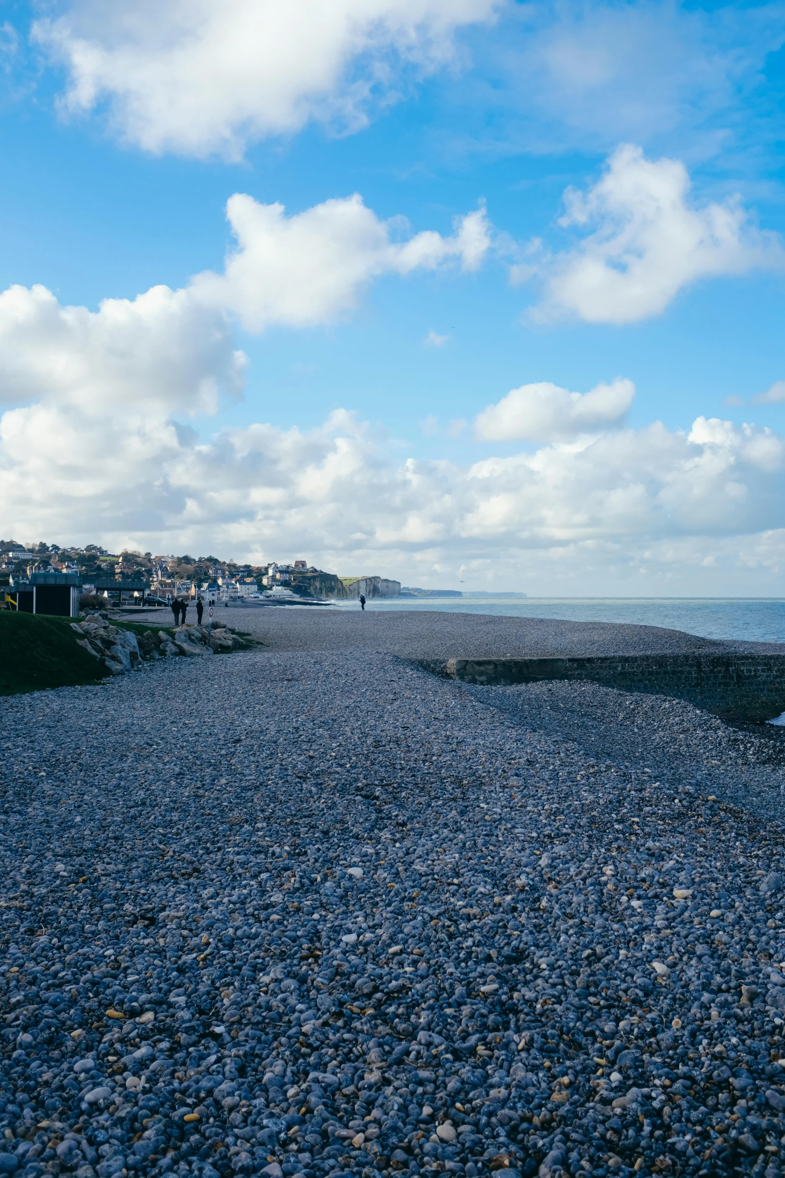 a bench sitting on top of a beach next to a body of water, inspired by Thomas Struth, mingei, blue cobblestones, walking to the right, gravels around, d - day