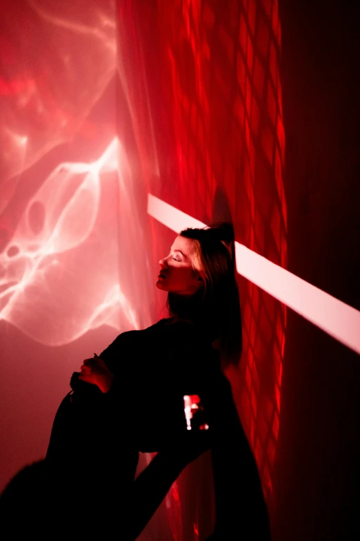 a person standing in front of a red light, interactive art, standing in a maelstrom, profile image, lightshow, looking partly to the left
