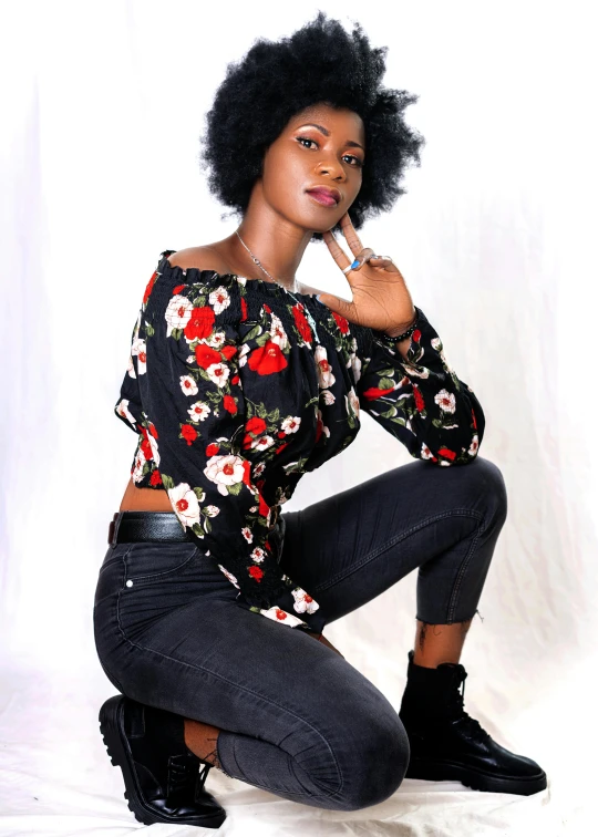 a woman sitting on the ground posing for a picture, by Chinwe Chukwuogo-Roy, pexels, happening, floral clothes, wearing a dark shirt and jeans, black curly hair, model standing pose