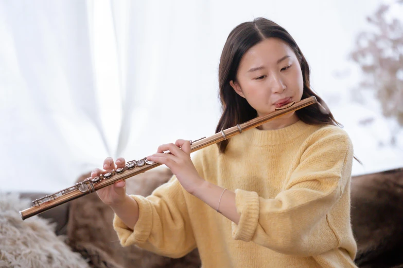 a woman in a yellow sweater playing a flute, inspired by Gu Kaizhi, trending on pexels, australian, yanjun chengt, petite, performing