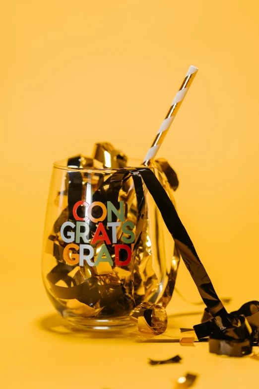 a glass filled with candy sitting on top of a table, black and gold wires, post graduate, with a straw, thumbnail