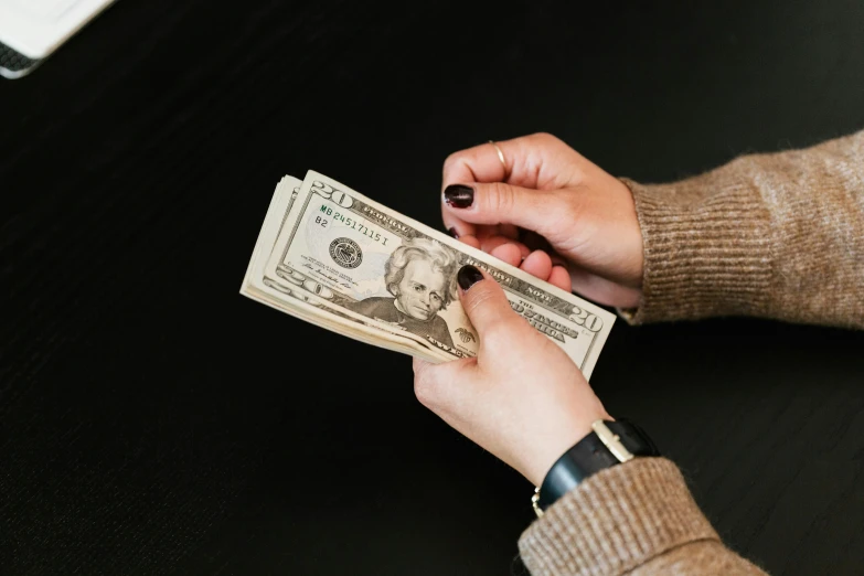 a woman holding a stack of one hundred dollar bills, by Byron Galvez, pexels contest winner, 🚀🌈🤩, slightly minimal, avatar image, hands on counter