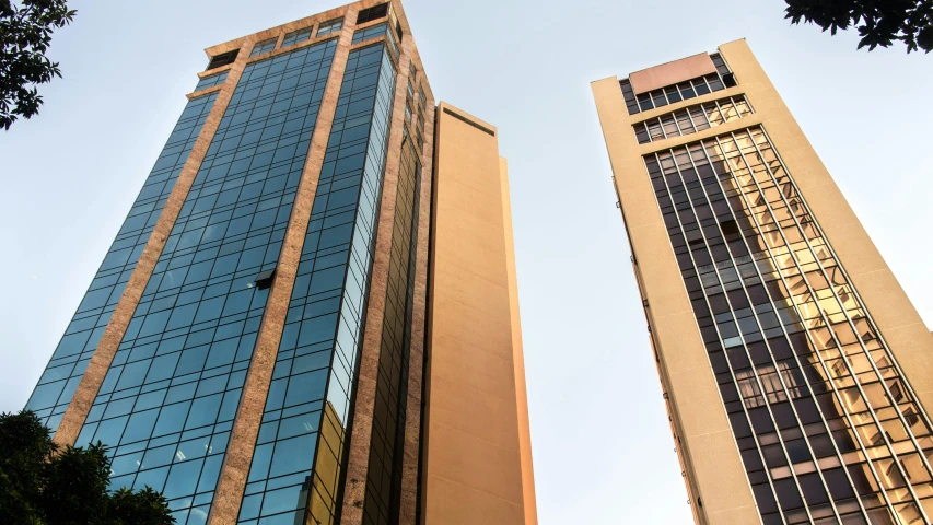 a couple of tall buildings next to each other, a picture, hurufiyya, brown, commercial, upright, exterior shot